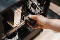 Close-up shot of a hand connecting cables in a computer tower, illustrating tech maintenance.